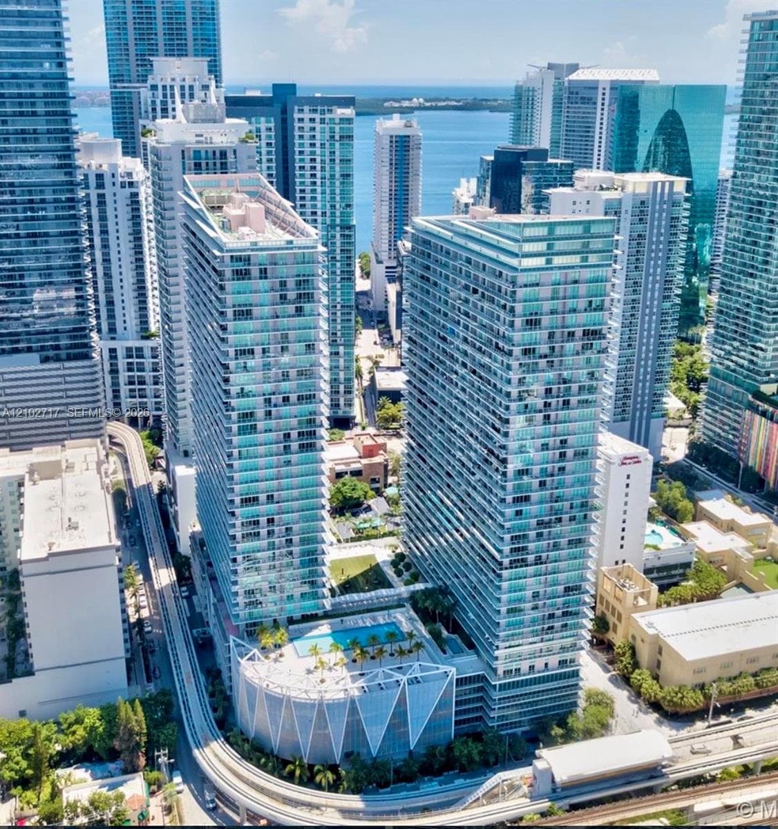 High-rise residential towers featuring glass facades, expansive balcony railings, and a podium-level swimming pool with sun deck
