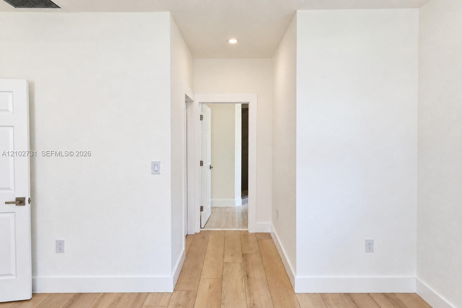 Neutral-toned walls, light-finished wood-finish flooring, recessed lighting, and white multi-panel doors with satin nickel hardware