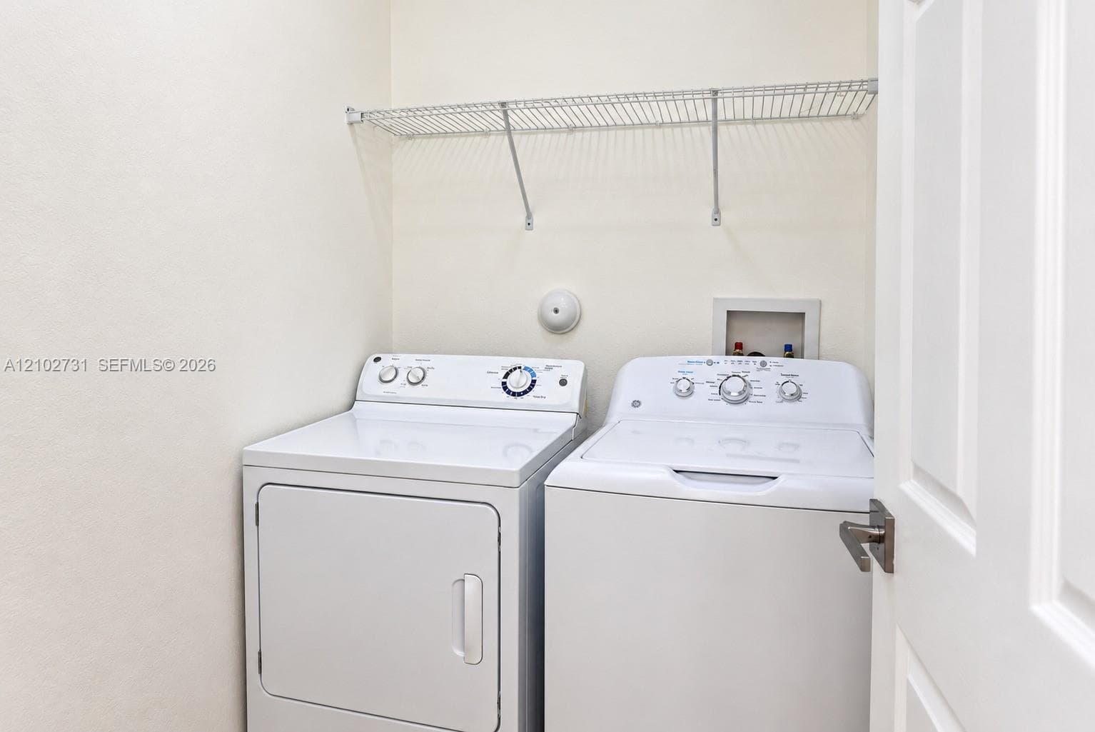 Laundry space featuring a built-in wire shelving unit and hookups for a washer and dryer