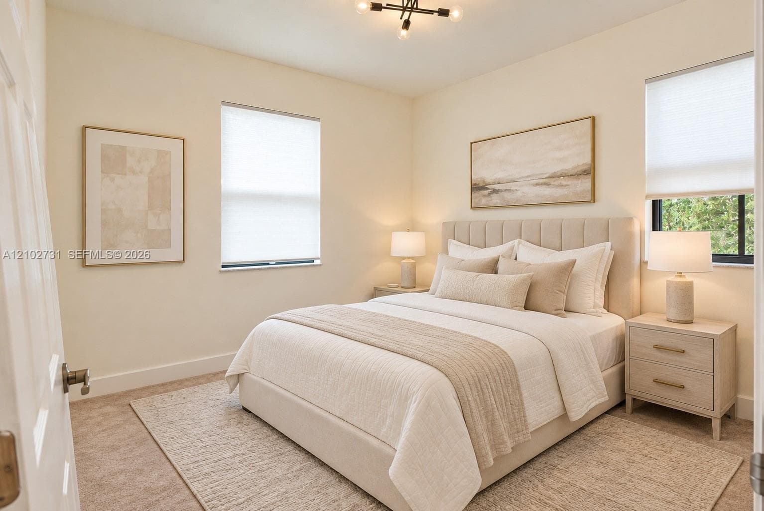 Neutral-toned room featuring wall-to-wall carpeting, dual windows equipped with pleated shades, and an exposed-bulb modern geometric ceiling light fixture