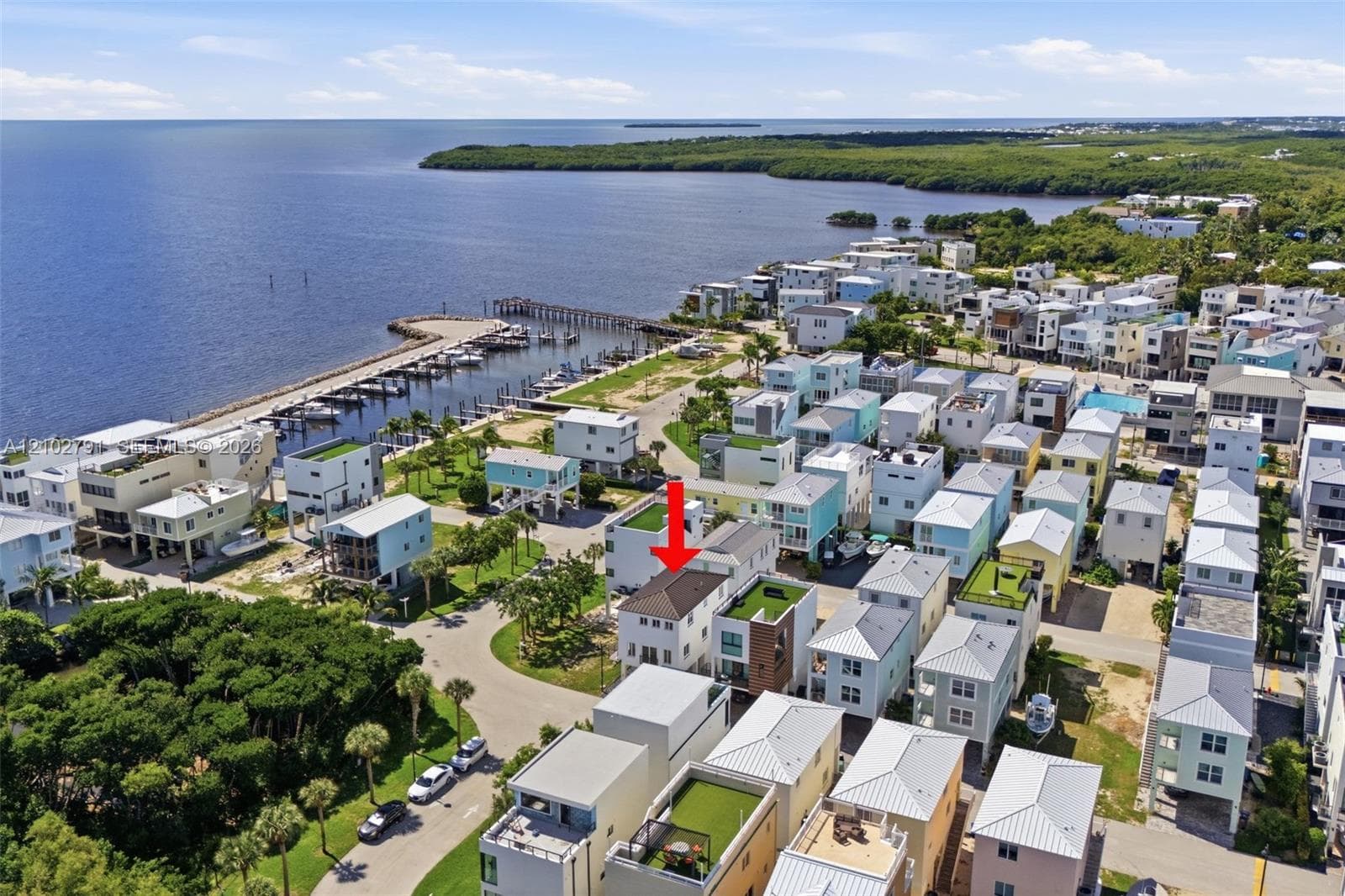 Aerial perspective of a multi-level residence featuring a pitched roof, light-toned exterior cladding, and proximity to the coastline