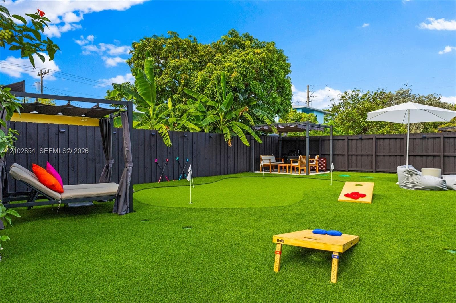 Private backyard featuring artificial turf, a built-in putting green, and a dark-stained wood privacy fence