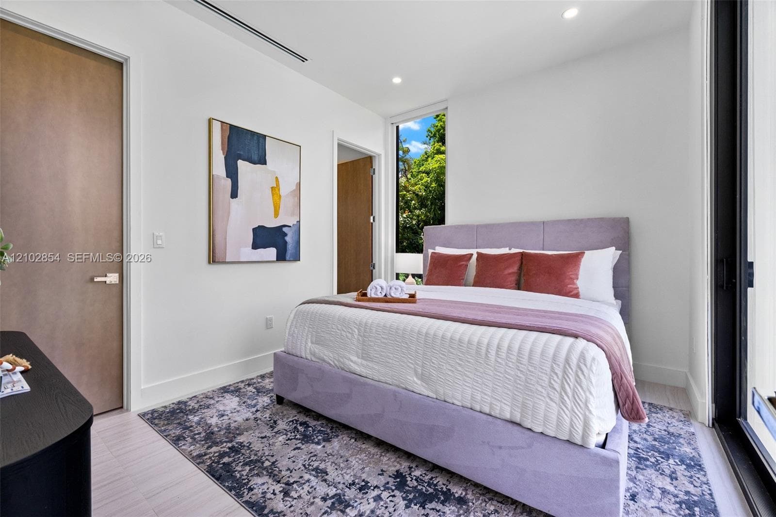 Minimalist bedroom featuring floor-to-ceiling windows, recessed lighting, smooth-finish interior doors, and pale wood-finish flooring