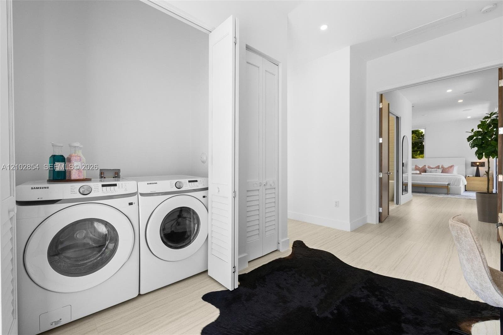 Laundry area featuring wood-finish flooring, white louvered-door closets, and recessed lighting