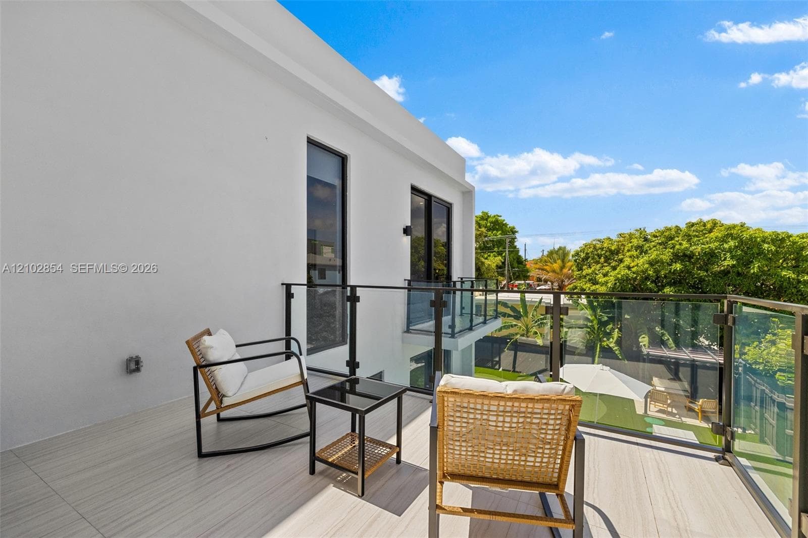 Outdoor balcony featuring light-toned tile flooring and a minimalist glass-panel railing with black metal hardware