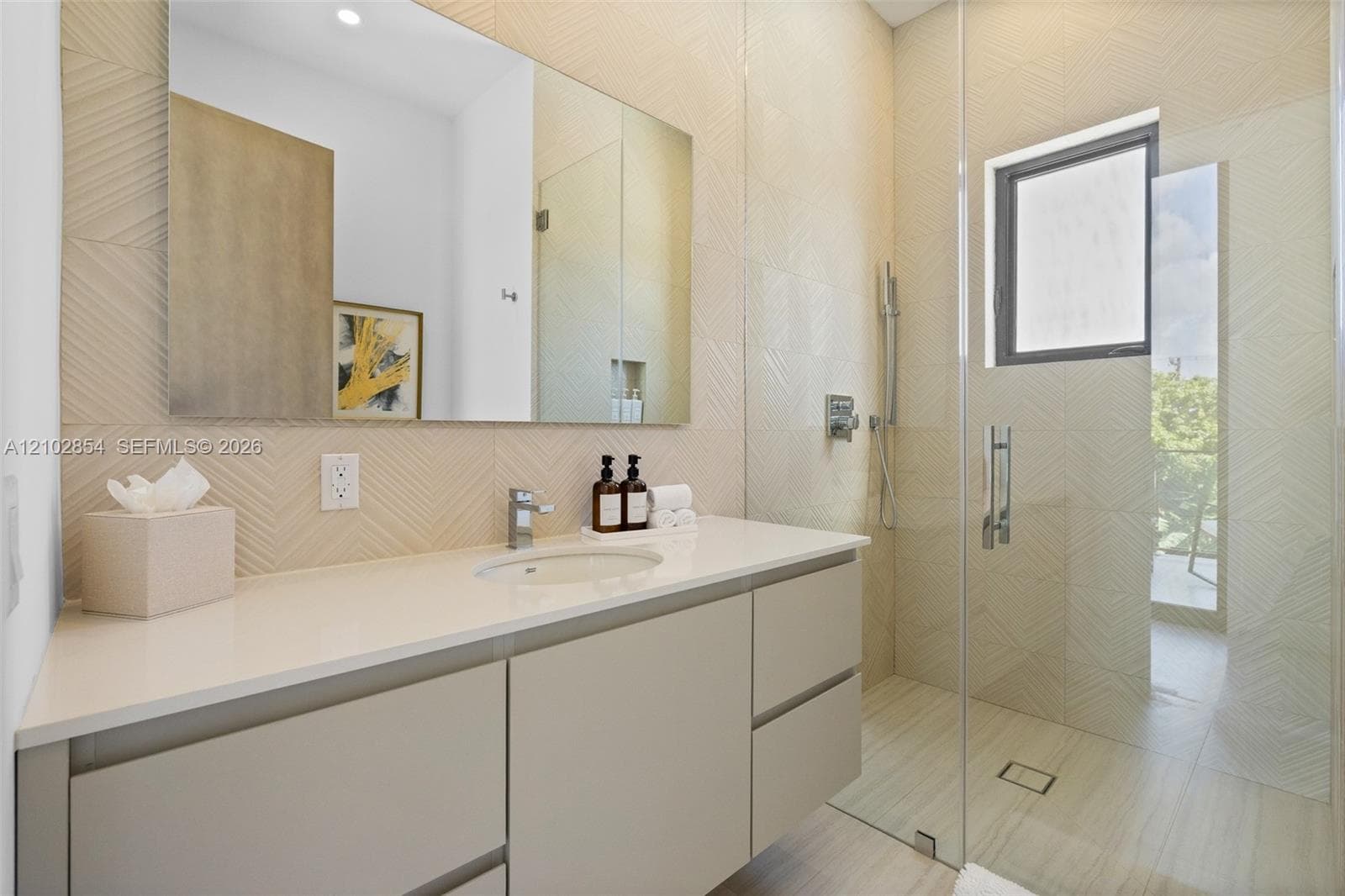 Bathroom featuring a floating vanity with a stone countertop, an integrated sink, a frameless glass-enclosed shower, and textured wall tile