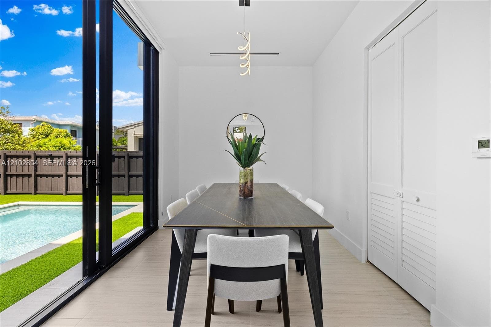 Floor-to-ceiling sliding glass doors, neutral tile flooring, modern pendant lighting, and white louvered closet doors
