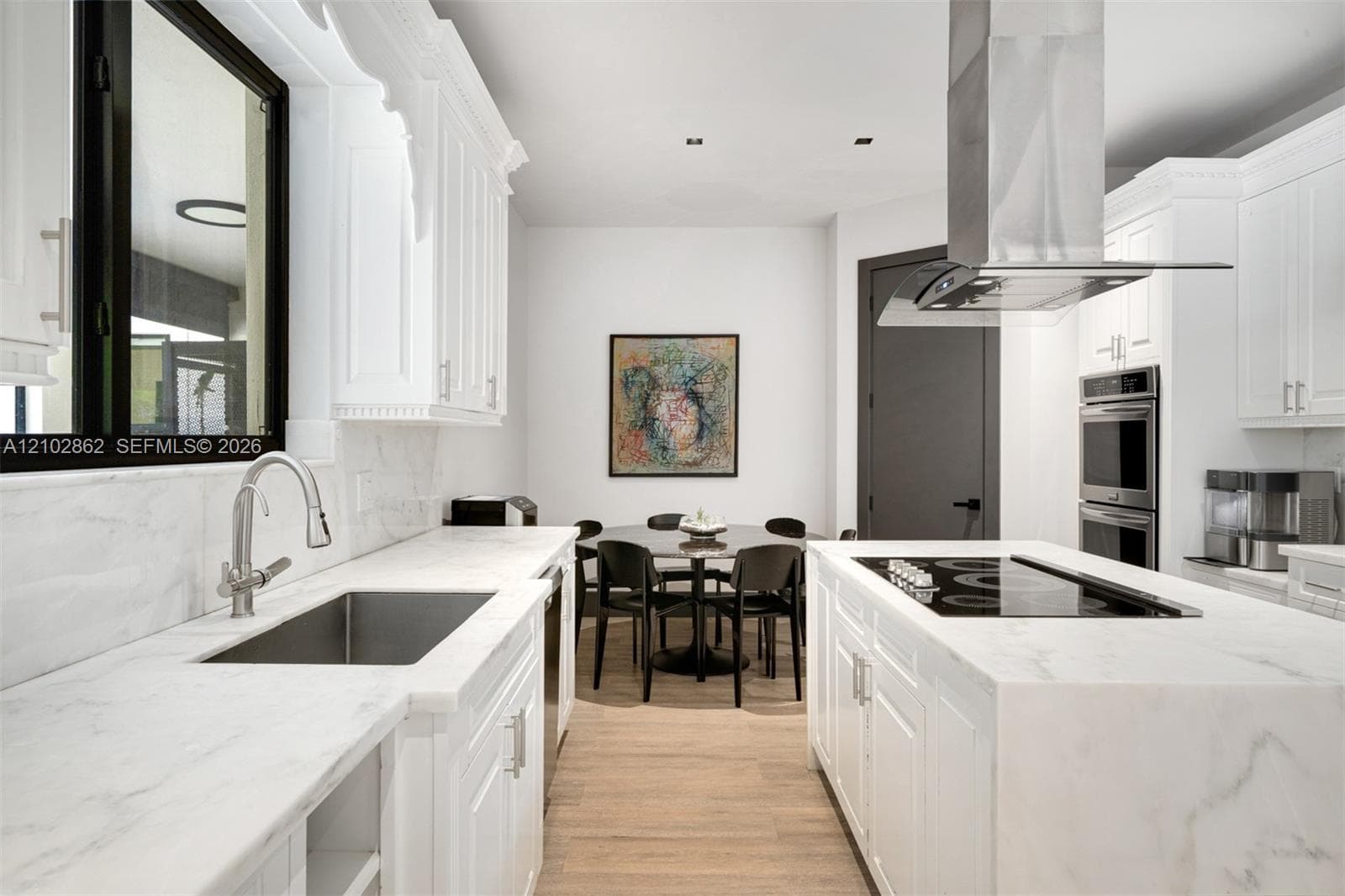 Kitchen featuring white cabinetry, stone countertops, stainless steel undermount sink, built-in double wall oven, and wood-finish flooring