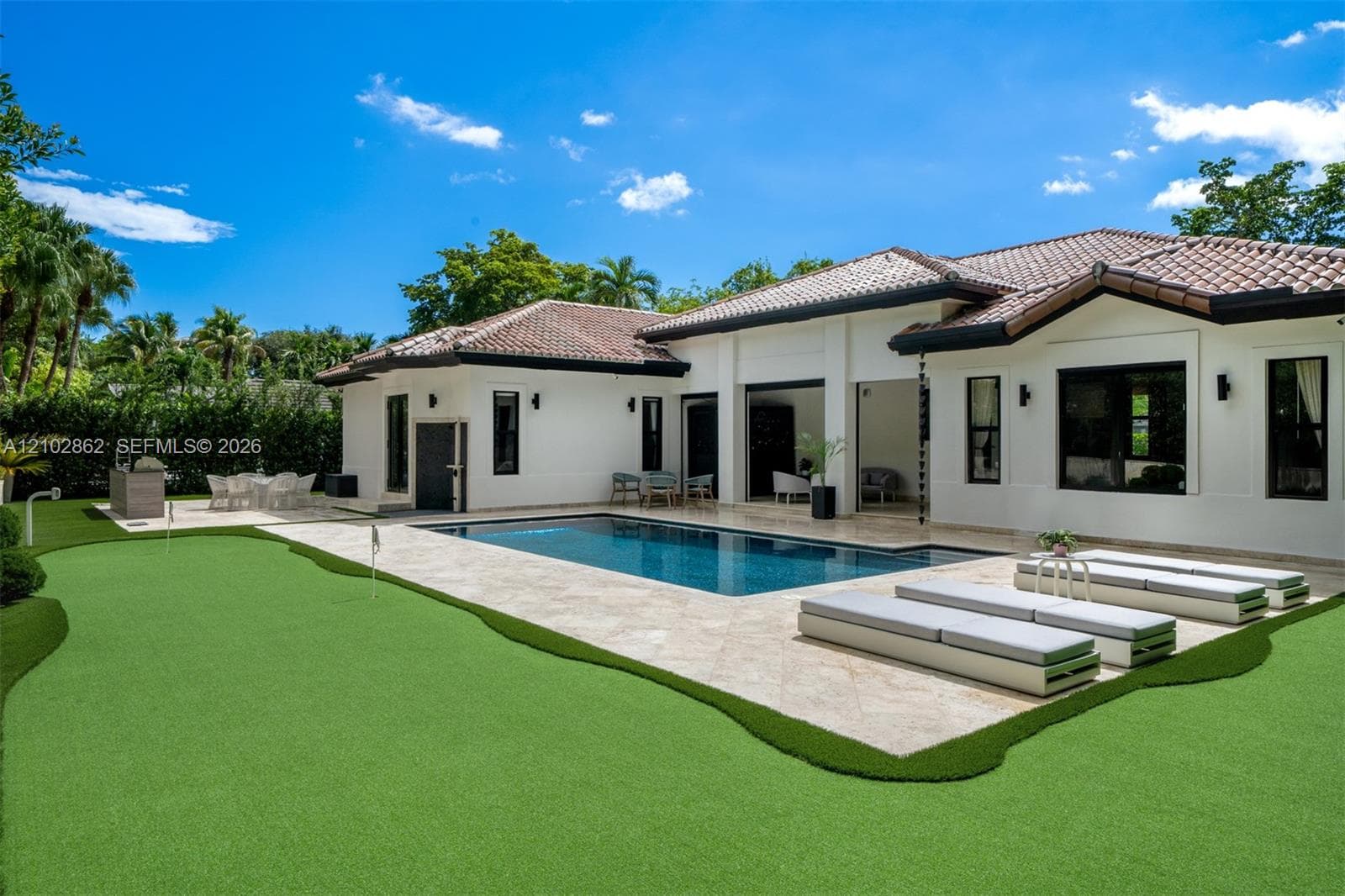 Exterior featuring a stucco facade, tile roof, swimming pool with stone decking, and an integrated putting green