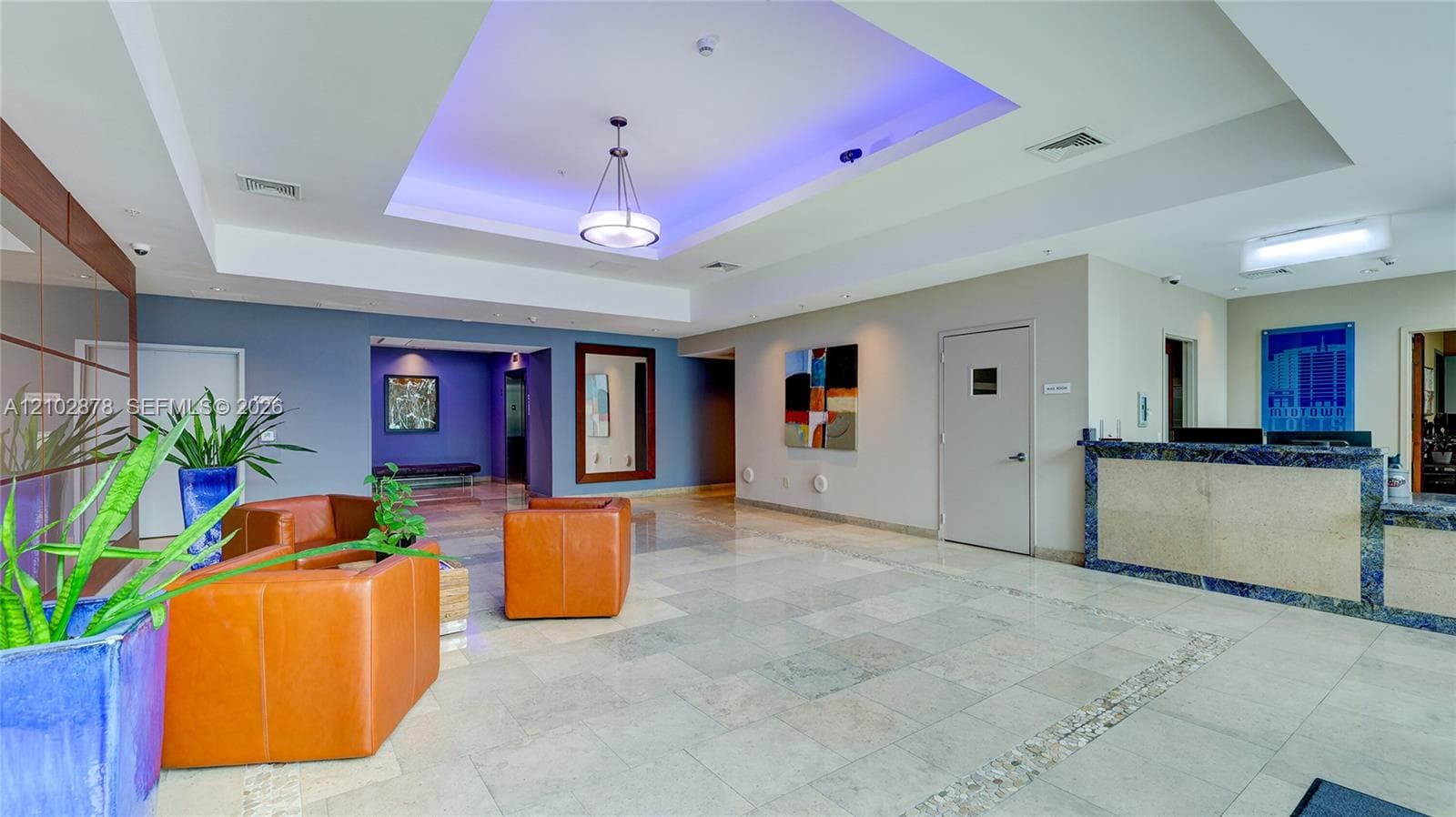 Lobby area featuring recessed ceiling detail with integrated lighting, polished stone flooring, and a stone-clad reception desk