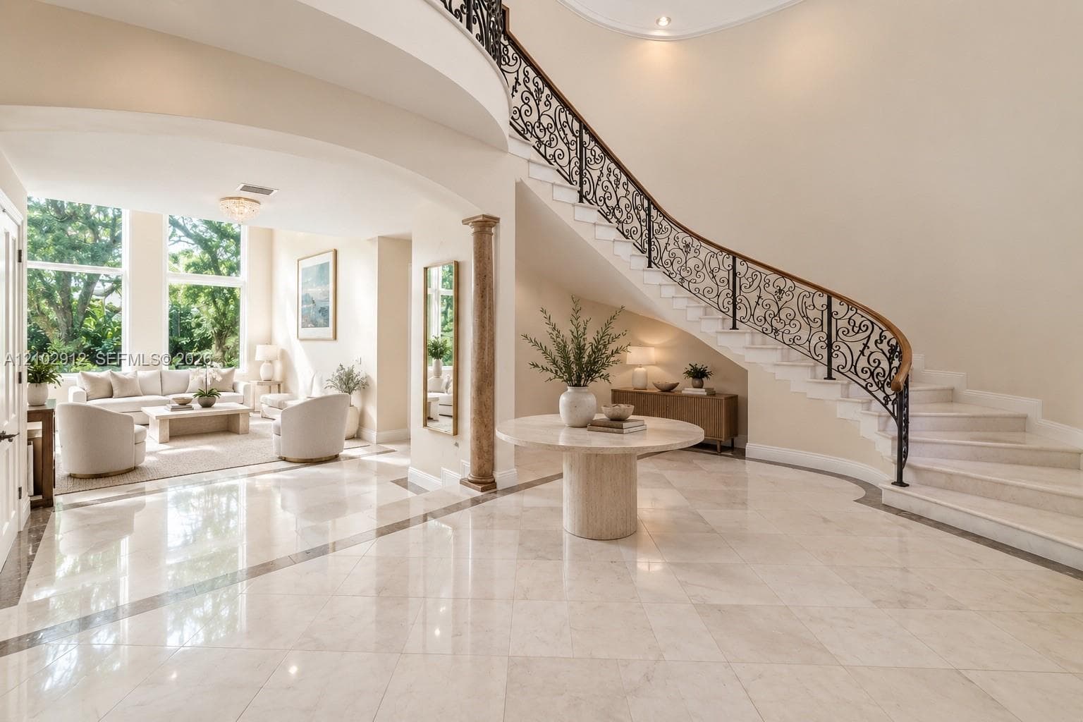 Grand foyer featuring a curved staircase with ornate wrought iron railing and wood handrail
