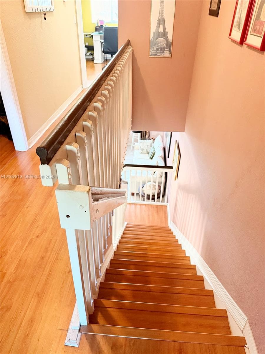 Staircase featuring wood-finish treads, a contrasting dark wood handrail, and white balusters
