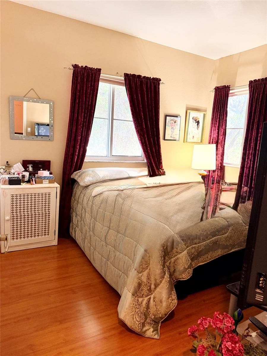 Wood-finish flooring, dual windows with grid inserts, and a built-in cabinetry unit with decorative lattice detailing