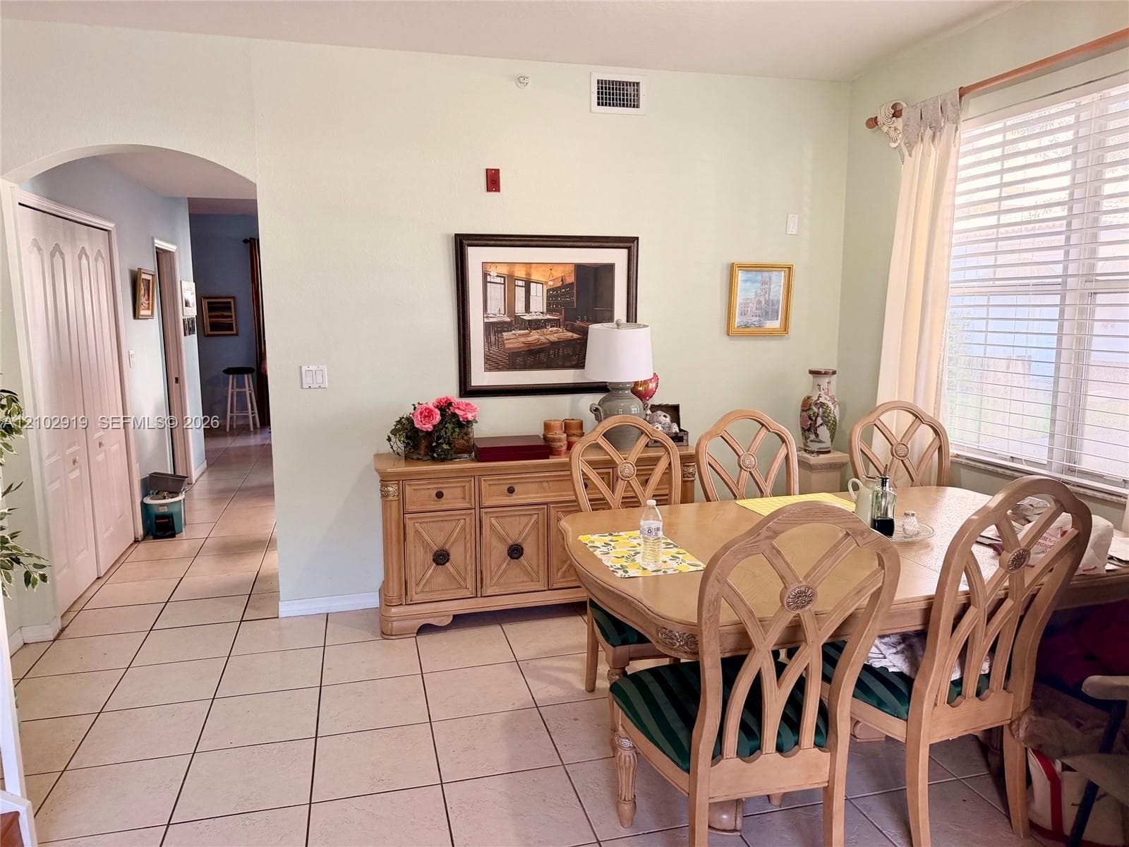 Ceramic tile flooring, arched entryway, and large window with horizontal blinds