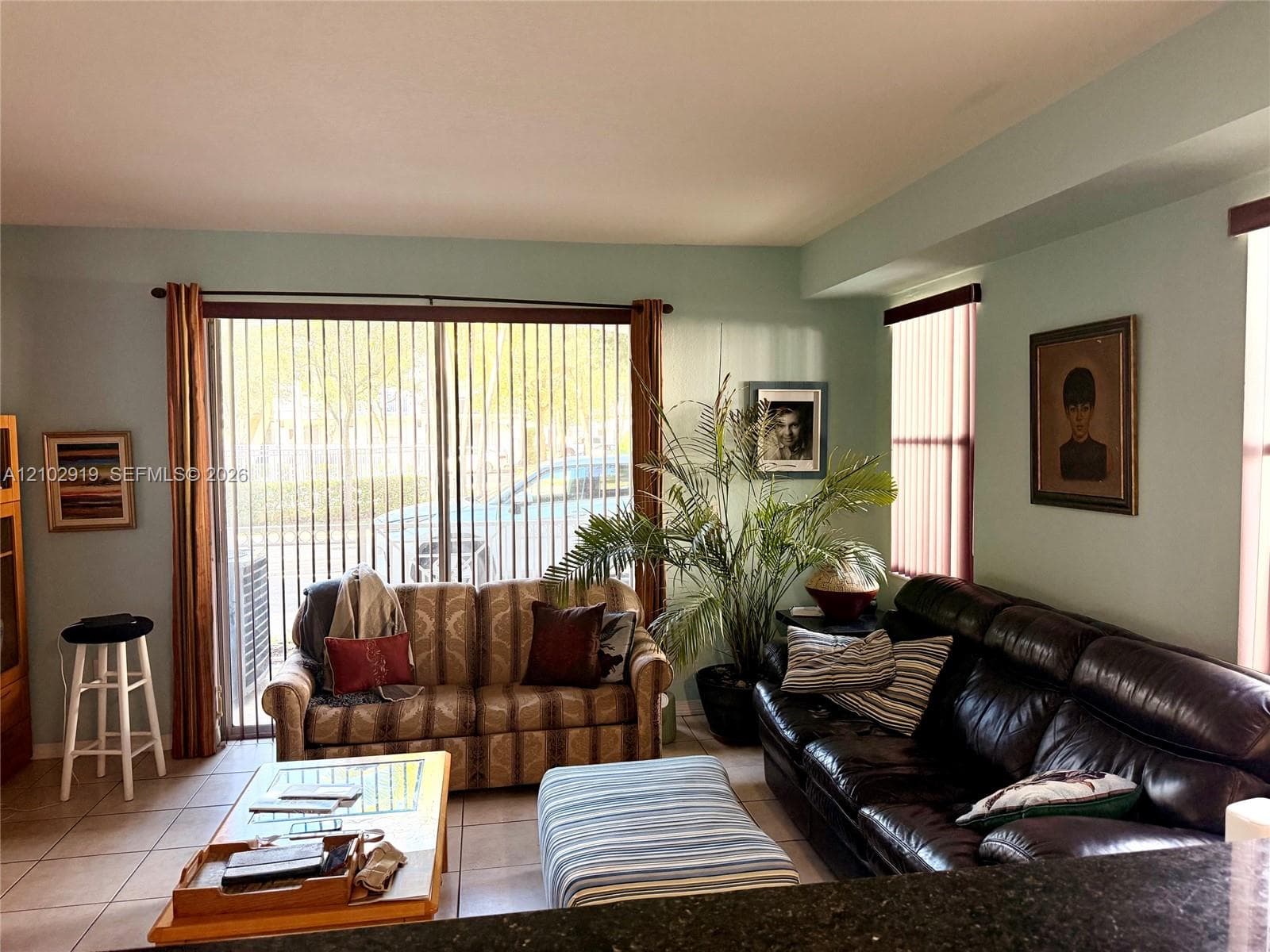 Living area featuring tile flooring and sliding glass doors with vertical blinds