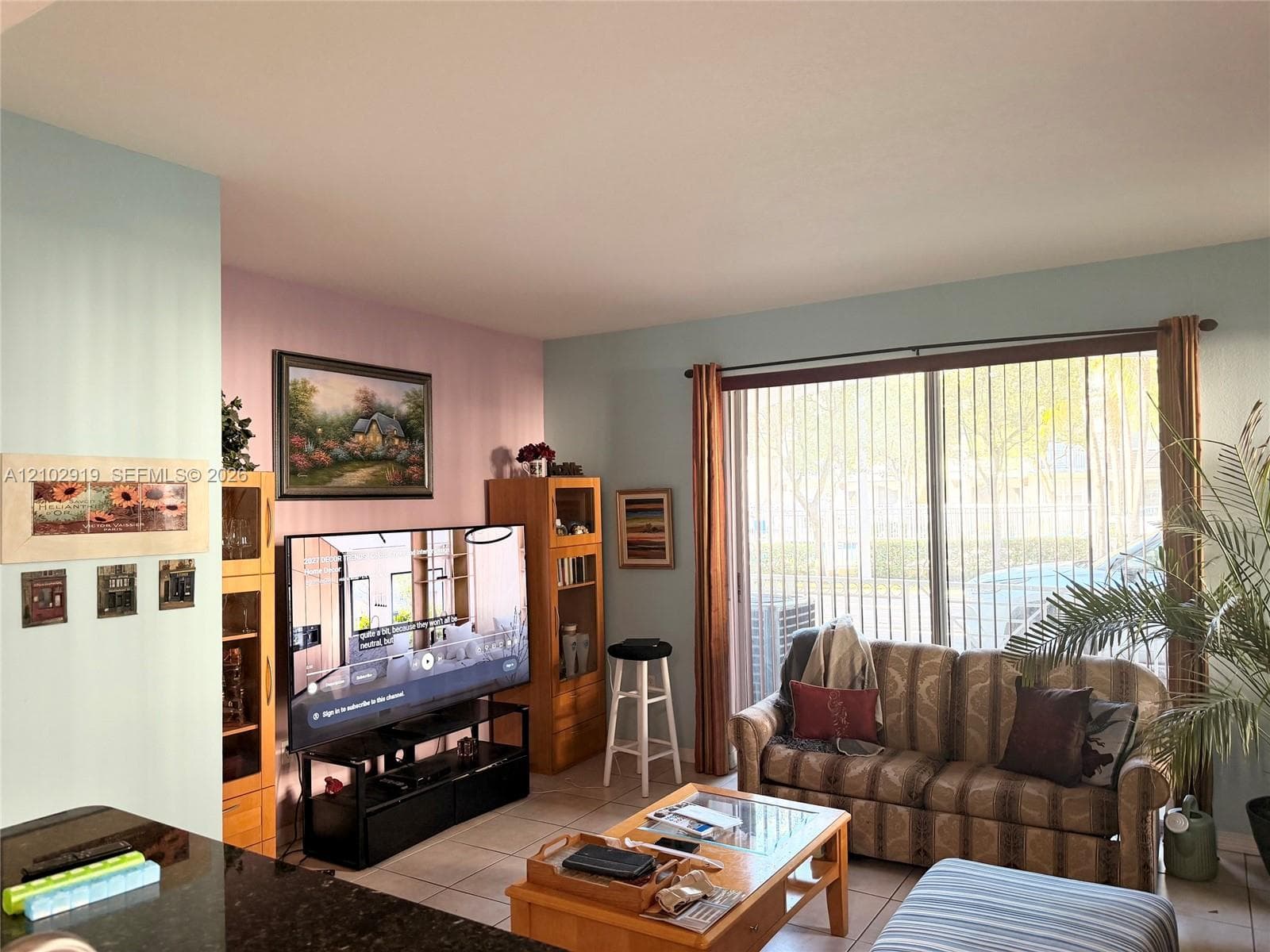 Living area featuring large sliding glass doors, neutral tile flooring, and light-toned wall paint