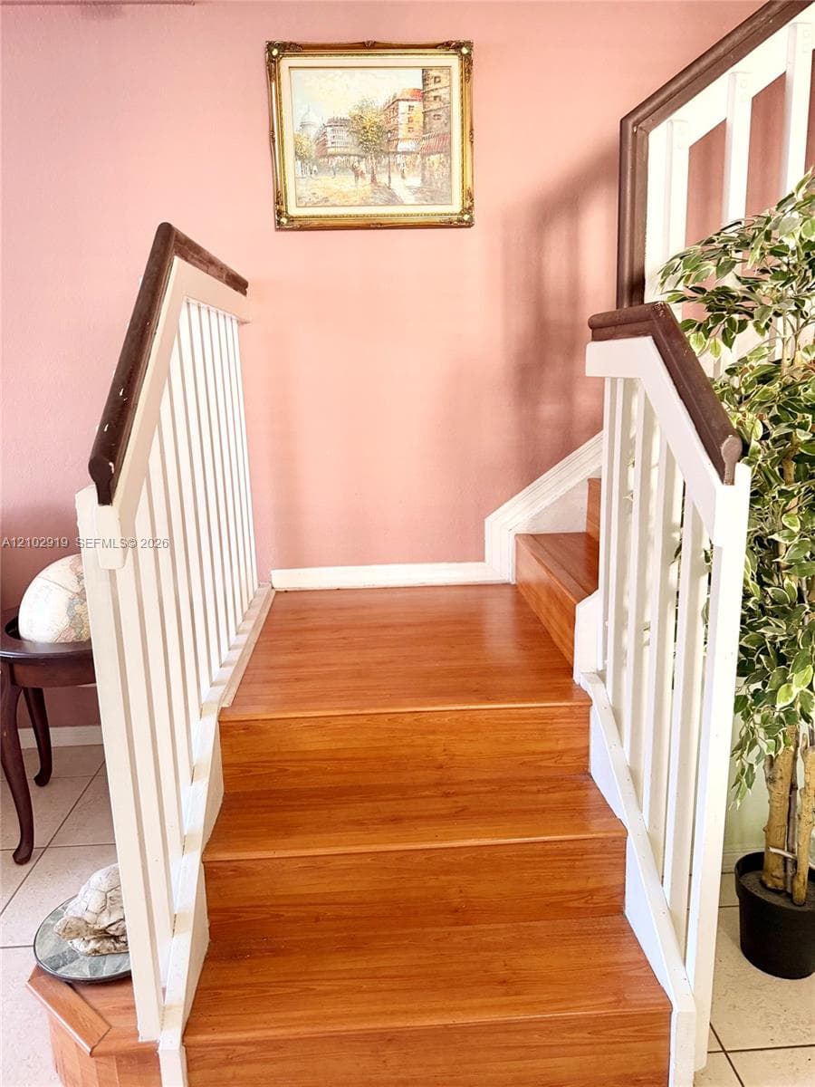 Staircase featuring wood-finish treads, white vertical balusters, and a dark wood handrail