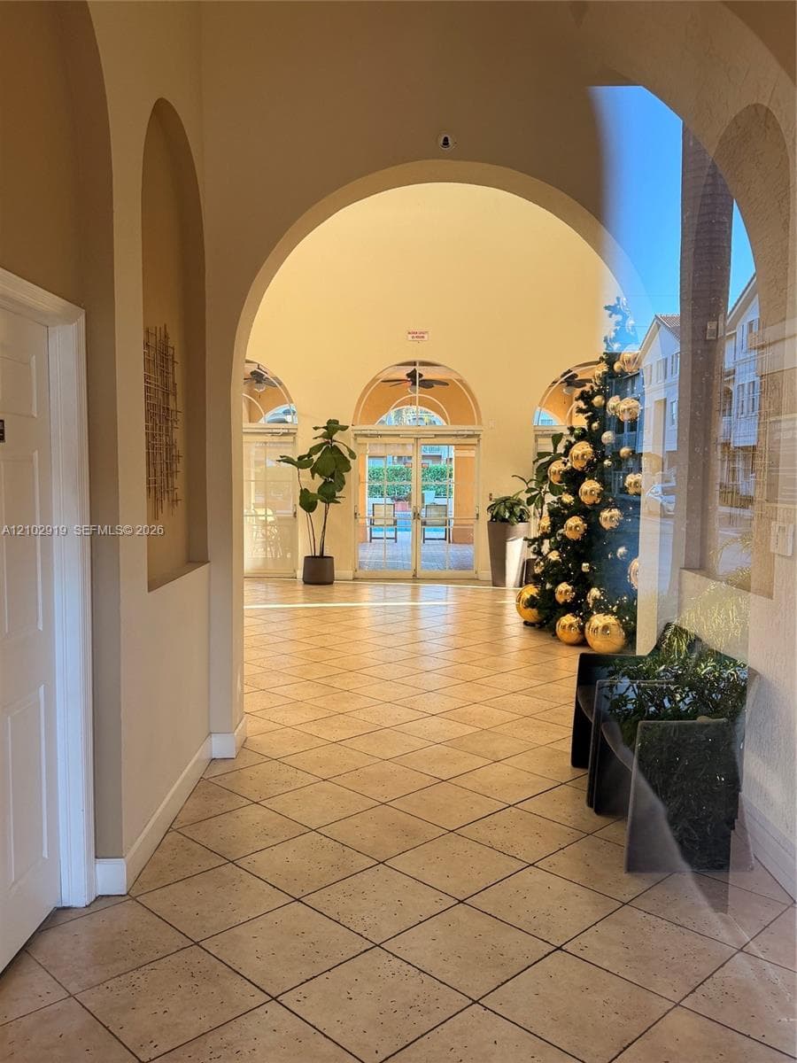 Grand entry featuring arched architectural detailing, ceramic tile flooring, and glass-paneled double doors