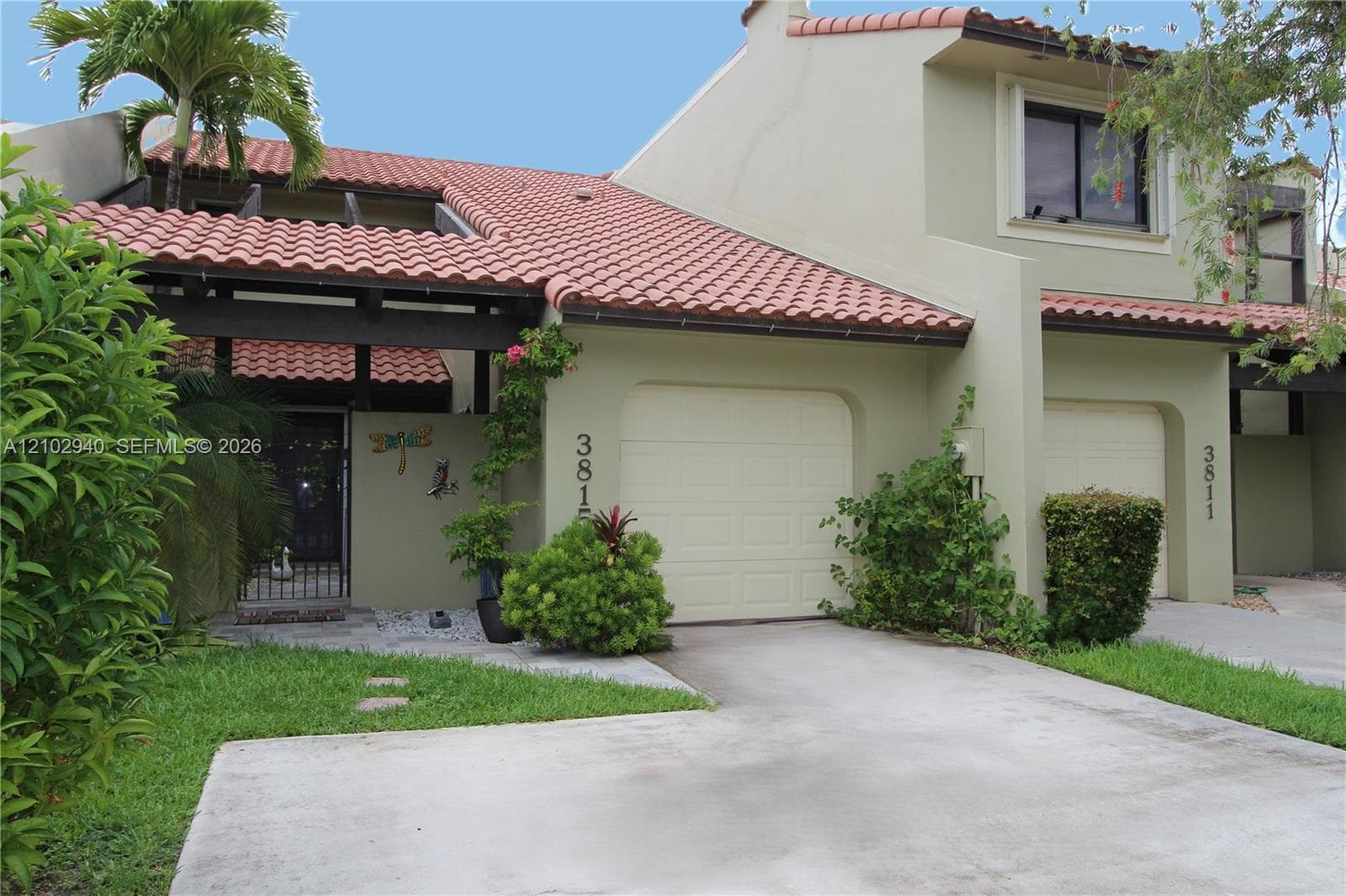 Exterior facade featuring clay tile roofing, stucco siding, a concrete driveway, an attached garage, and a gated entryway