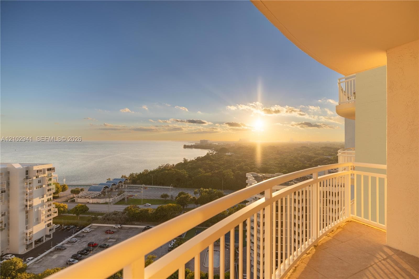 Covered outdoor balcony featuring white railings, tiled flooring, and sweeping panoramic ocean and coastal scenery