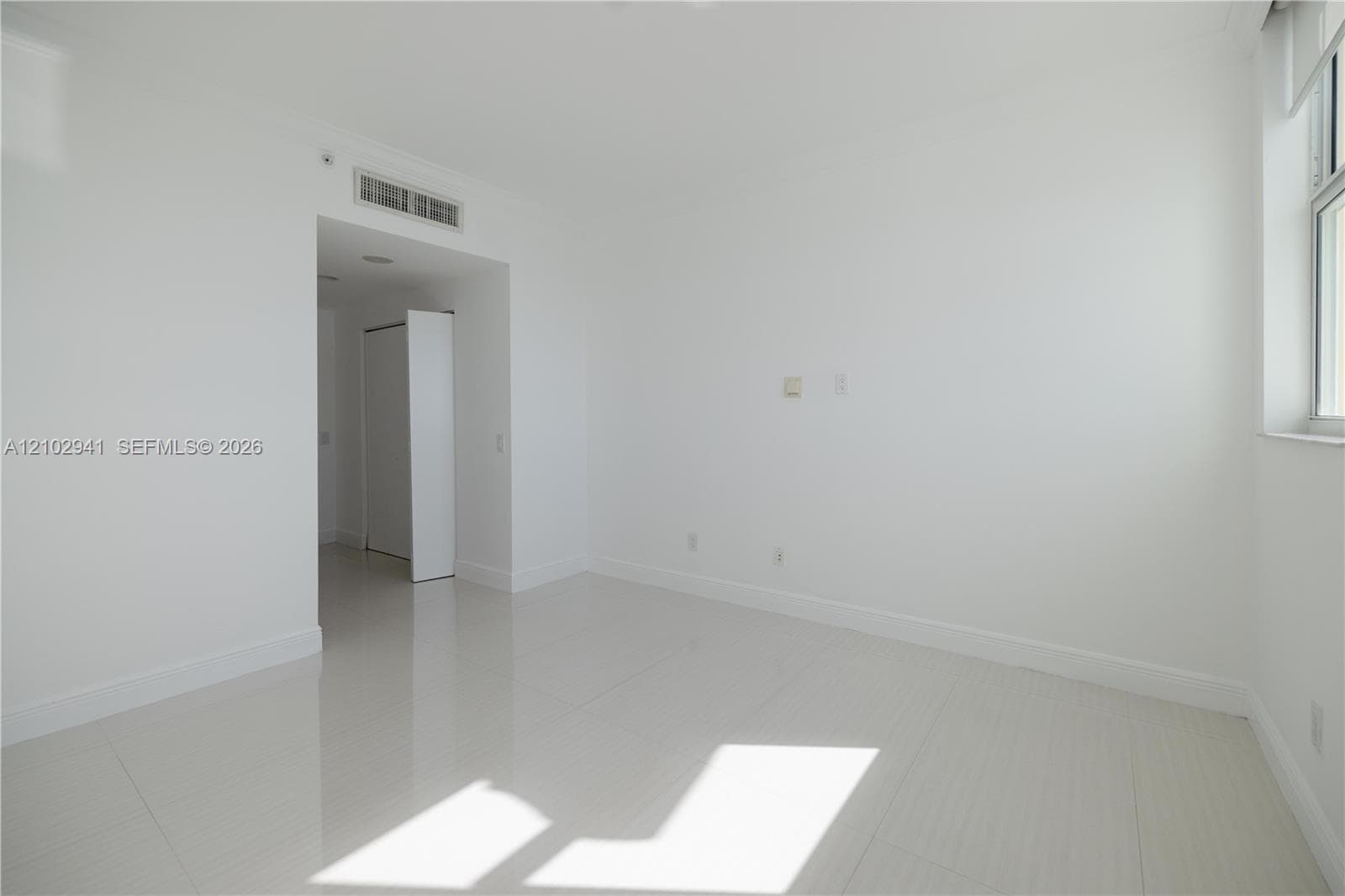 Interior space featuring polished tile flooring, neutral wall finishes, and a window with white casing