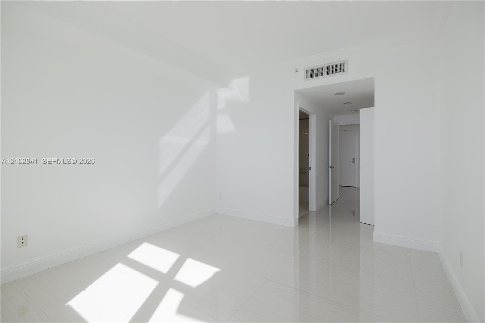 Neutral-toned interior space featuring polished tile flooring, recessed ceiling lighting, and smooth-finish walls