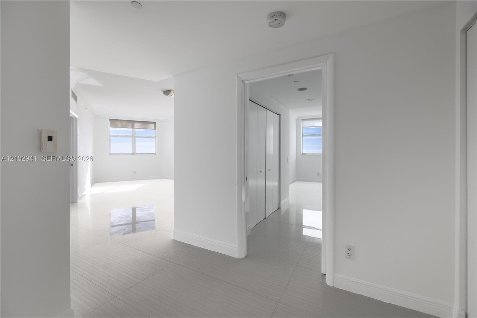 Interior space featuring polished tile flooring, white walls, and floor-to-ceiling closets with sliding panel doors
