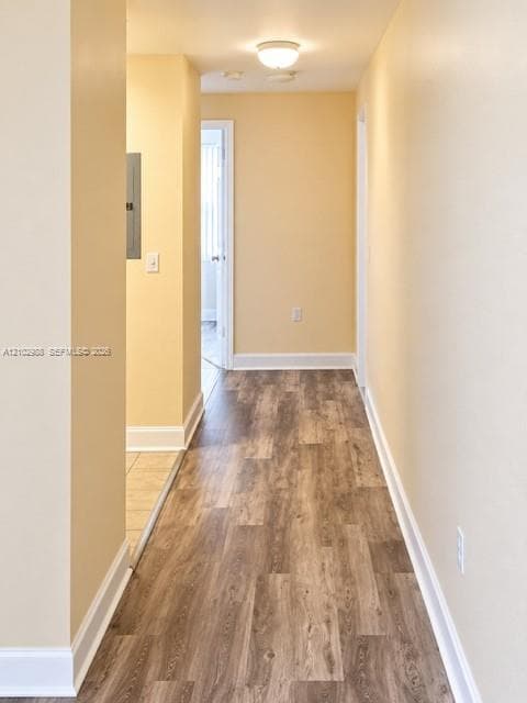 Hallway featuring wood-finish flooring, neutral wall paint, and a flush-mount ceiling light fixture