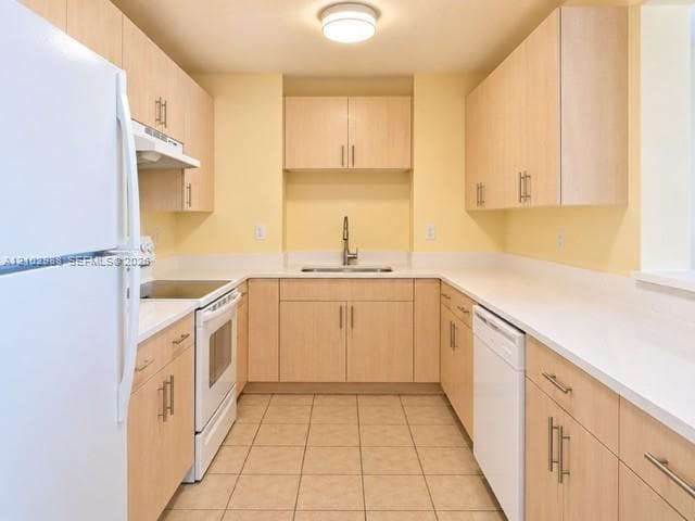 Kitchen featuring light-finish cabinetry, solid surface countertops, a stainless steel undermount sink with a gooseneck faucet, tile flooring, and white appliances