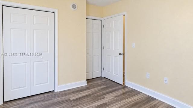Room featuring wood-finish flooring, two bi-fold closet doors, and a six-panel interior door