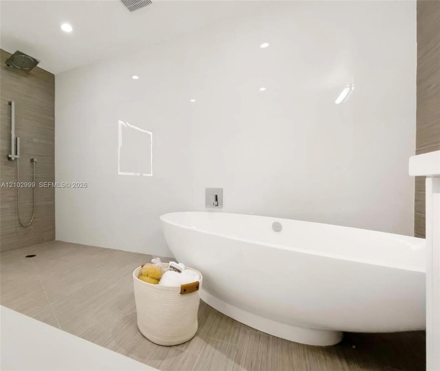 Freestanding soaking tub, large format tile flooring, recessed lighting, and a walk-in shower with a rainfall showerhead