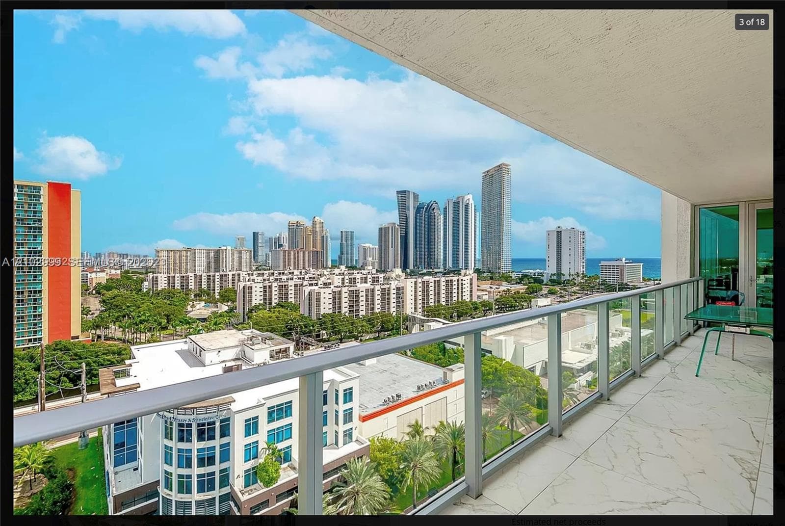 Expansive balcony featuring a glass and metal railing, textured tile flooring, and a broad city skyline