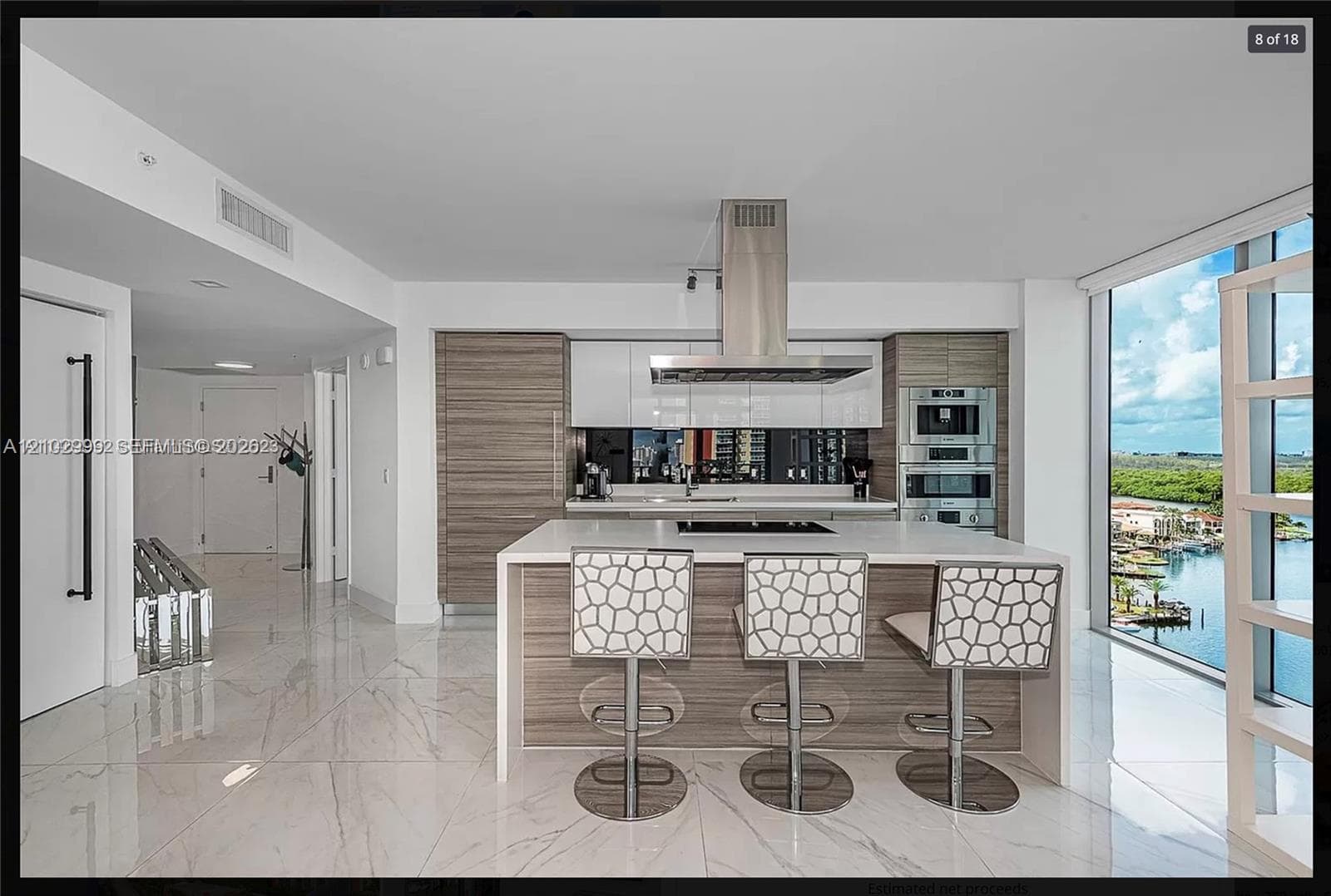 Gourmet kitchen with sleek flat-panel cabinetry, integrated stainless steel appliances, a center island with cooktop, and an undermount sink
