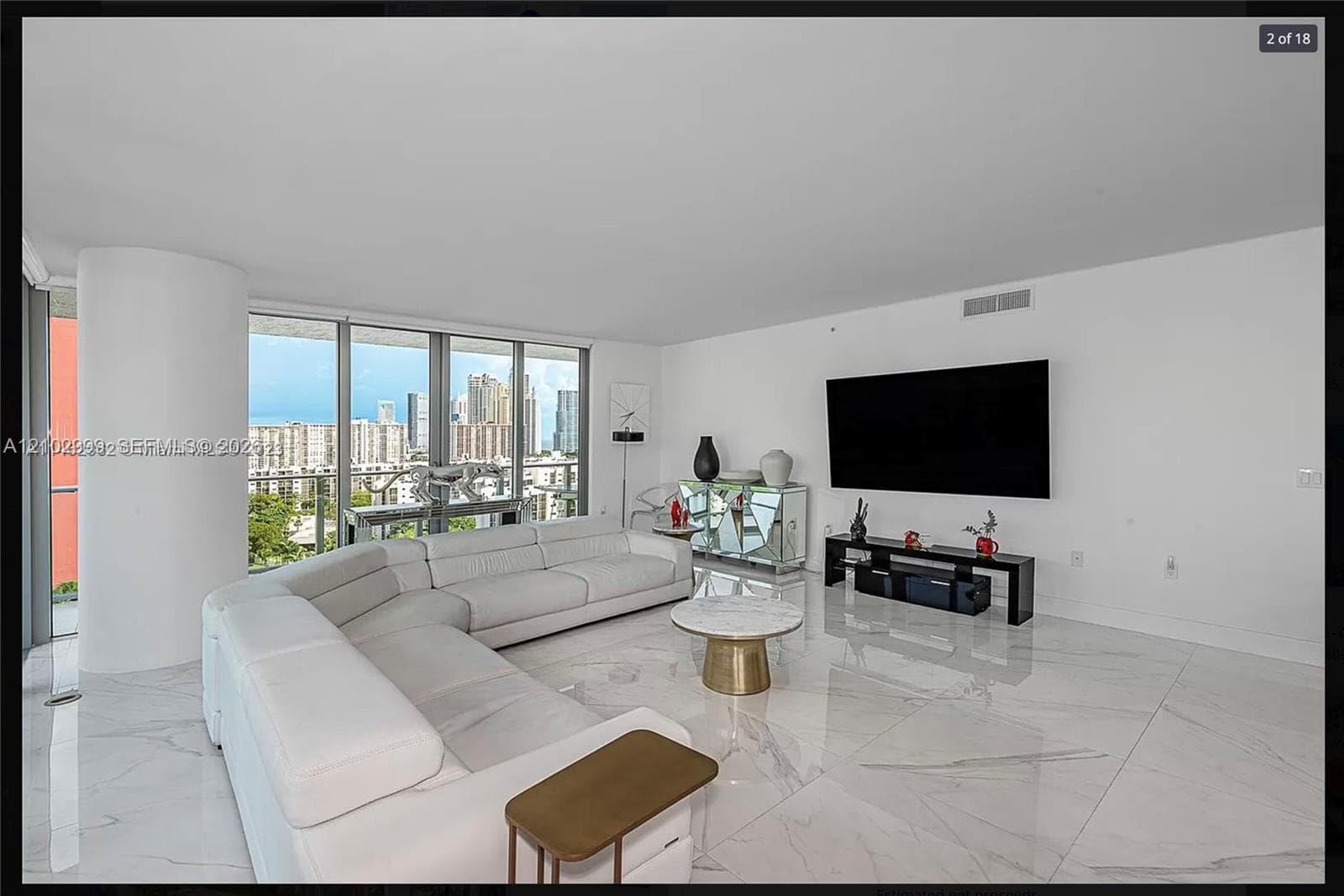Expansive room with large format tile flooring, a curved architectural column, and extensive window walls