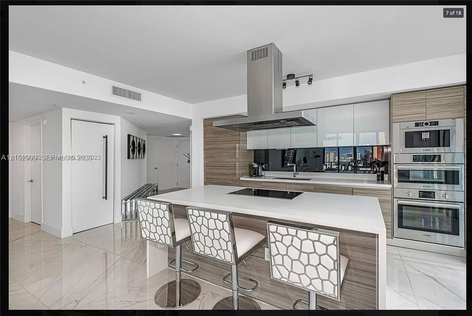 Spacious kitchen featuring an expansive island, integrated cooktop, stainless steel range hood, and built-in stainless steel appliances