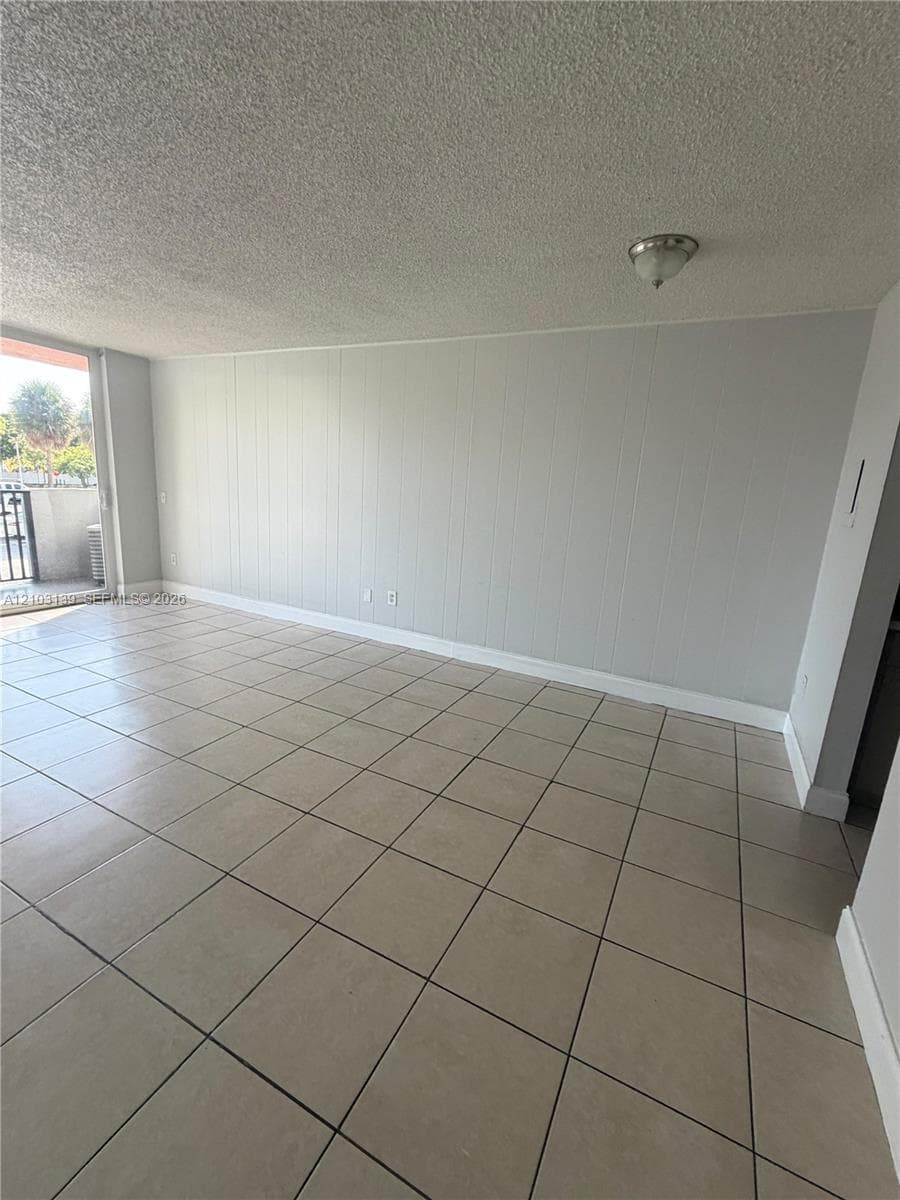 Light neutral-toned tile flooring, textured wall panels, and a flush-mount ceiling light