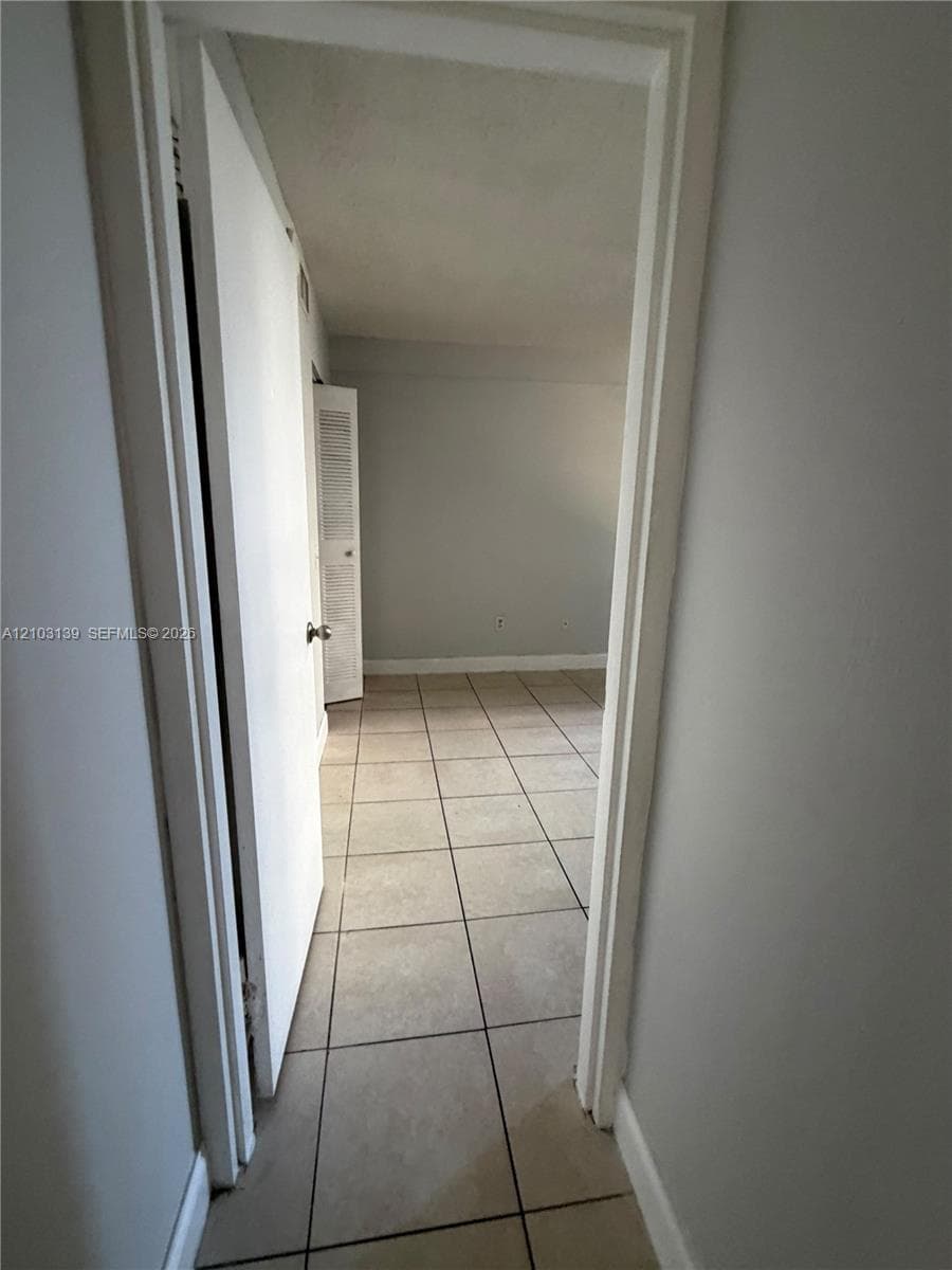 Tile flooring extends into the room, complemented by a white door and light-colored walls