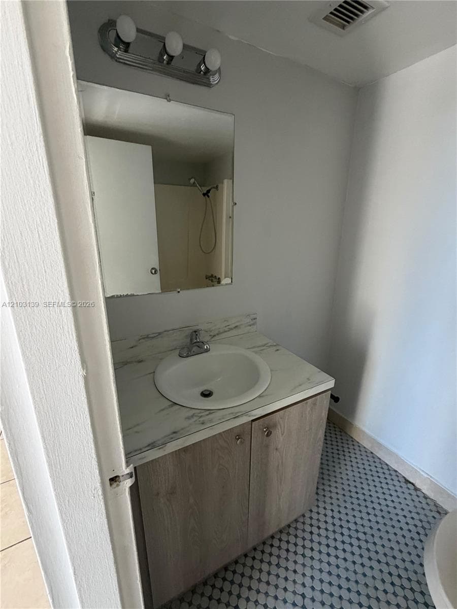 Vanity with a white basin sink, a patterned countertop, and wood-finish cabinetry