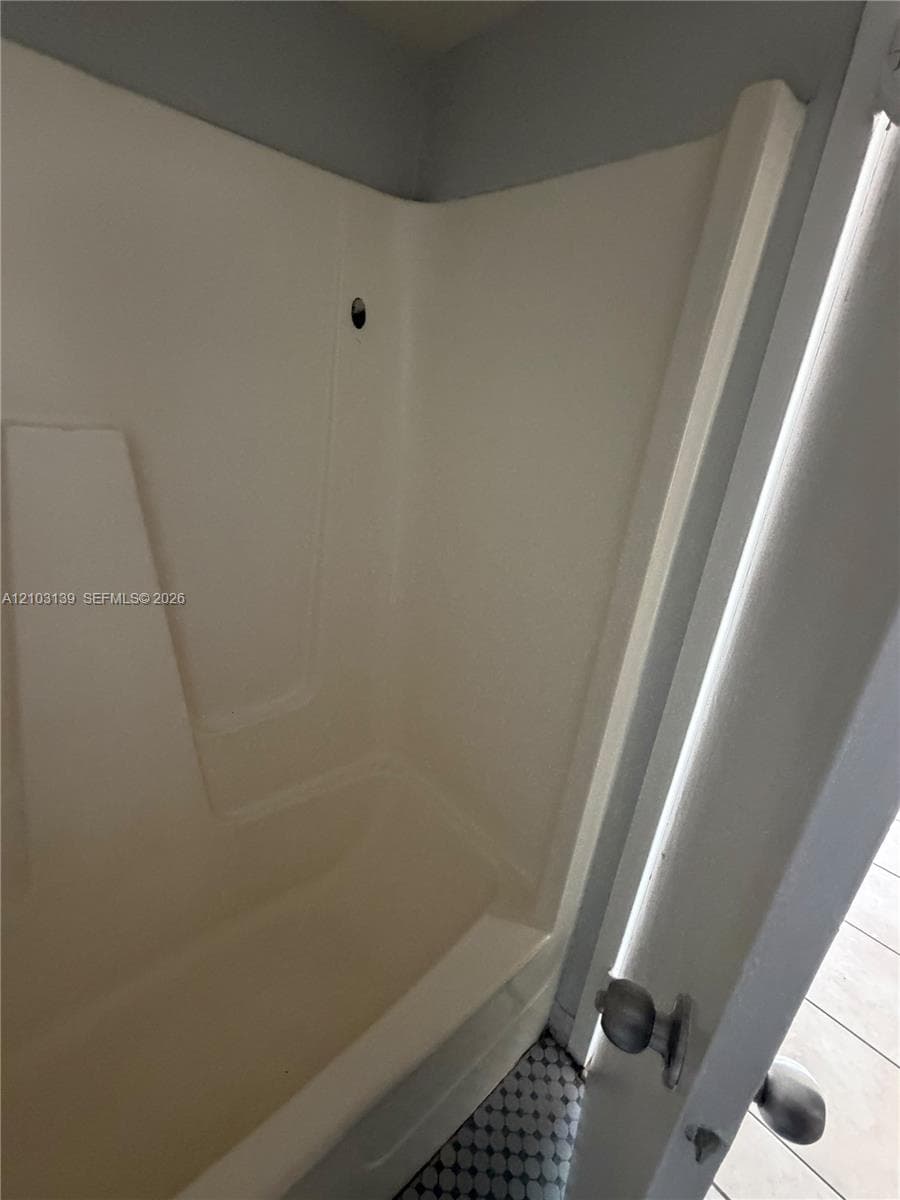 White fiberglass tub and shower combination with an integrated seat
