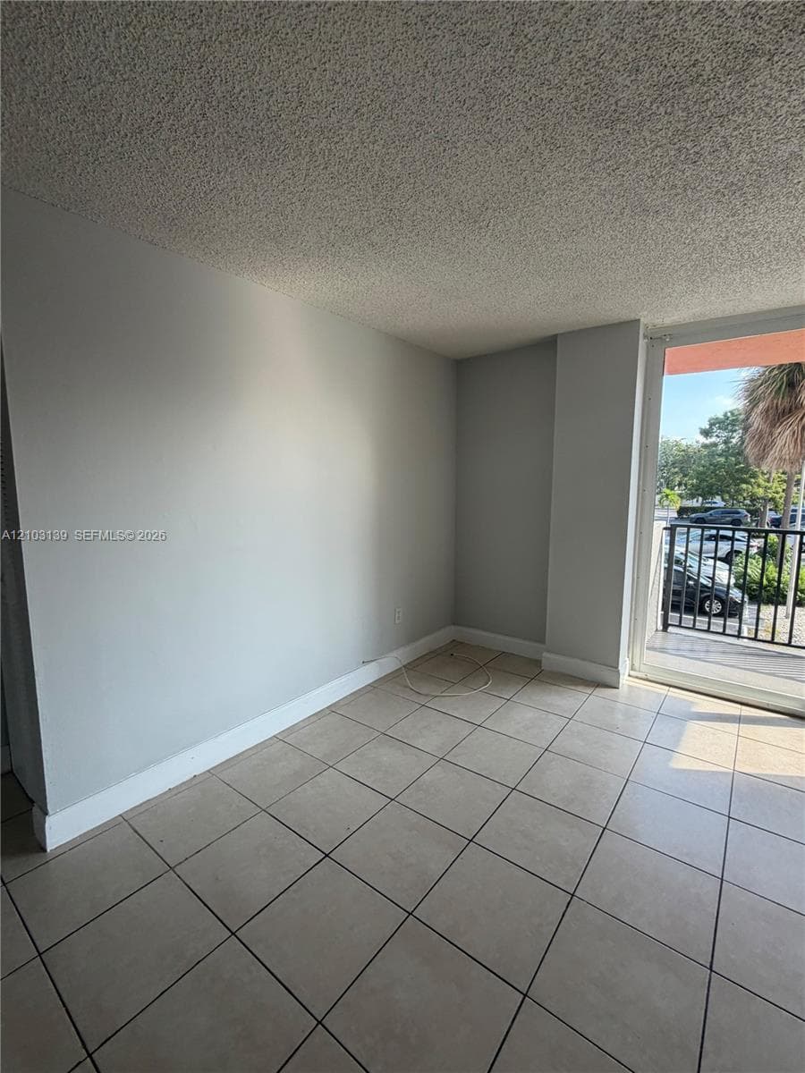 Tiled flooring with a diagonal pattern, light gray walls, and a private balcony with a black metal railing