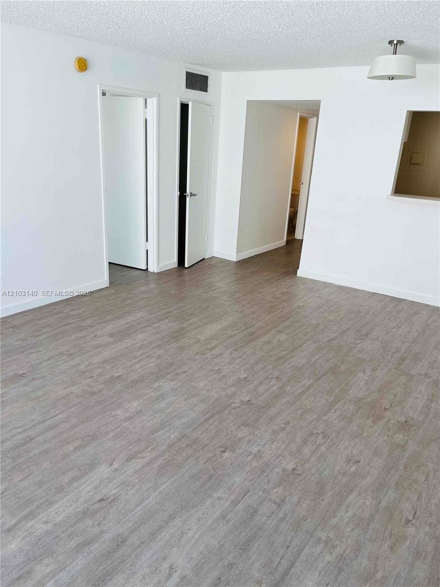 Open-concept space featuring wood-finish flooring, a neutral color palette, and a drum-style ceiling light fixture
