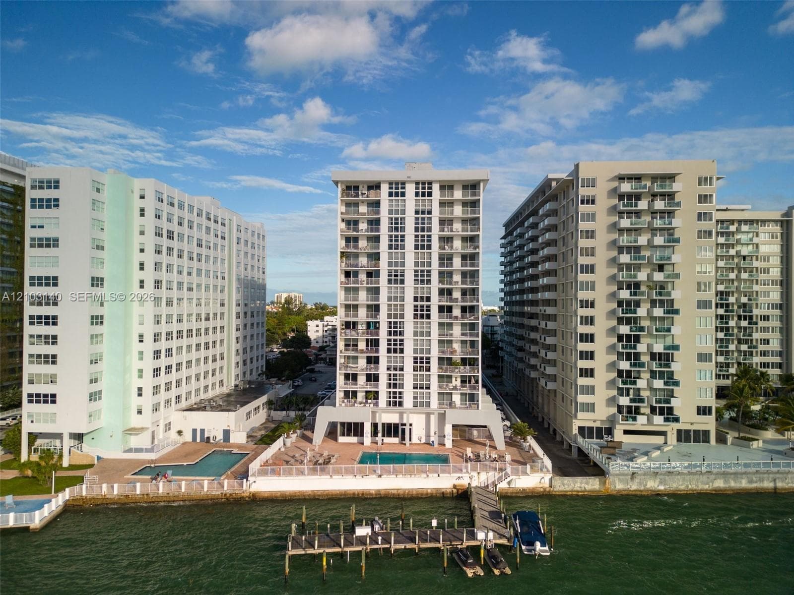 High-rise residential exterior featuring private balconies, ground-level pool, and a dedicated deep-water boat dock