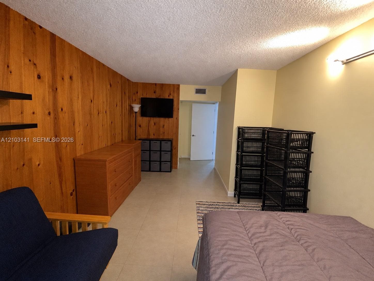 Interior space featuring wood-panel accent wall and neutral tile flooring