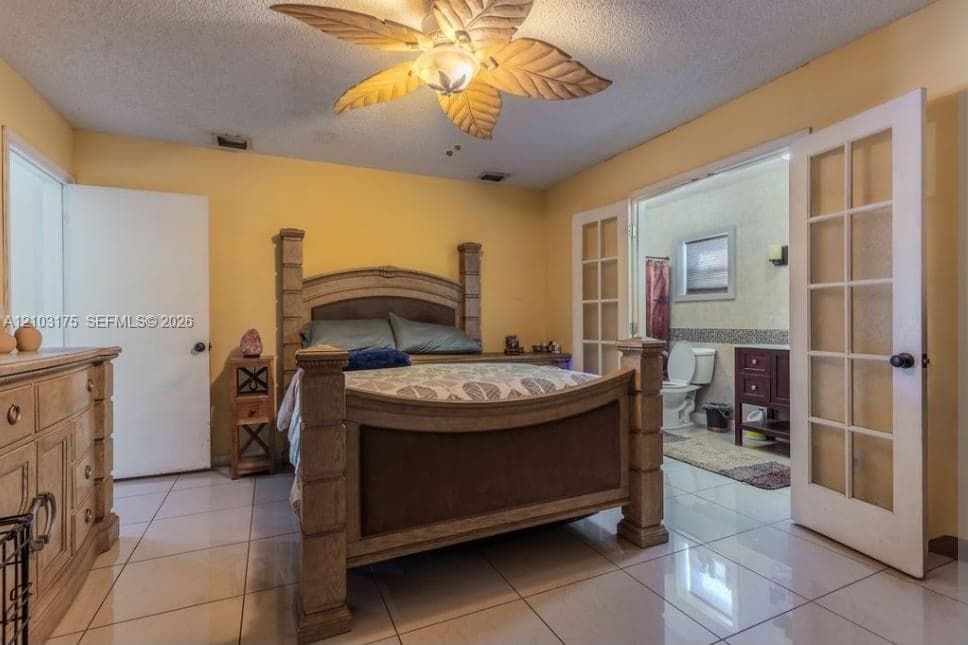 Ceramic tile flooring, palm leaf-style ceiling fan, and white-trimmed French doors