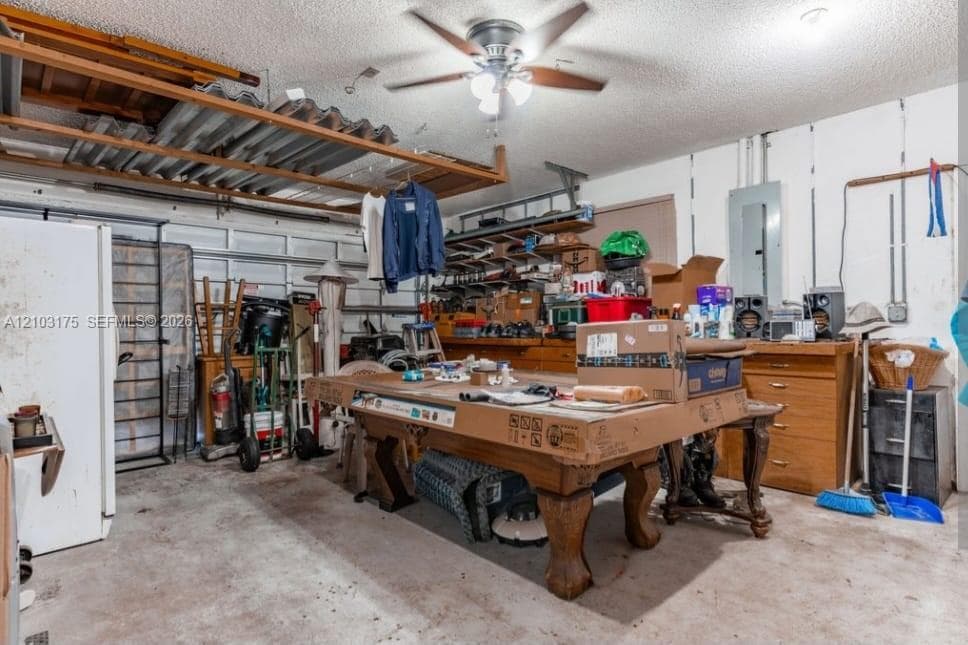 Garage space featuring built-in wooden cabinetry, ceiling fan with integrated lighting, and overhead metal storage shelving