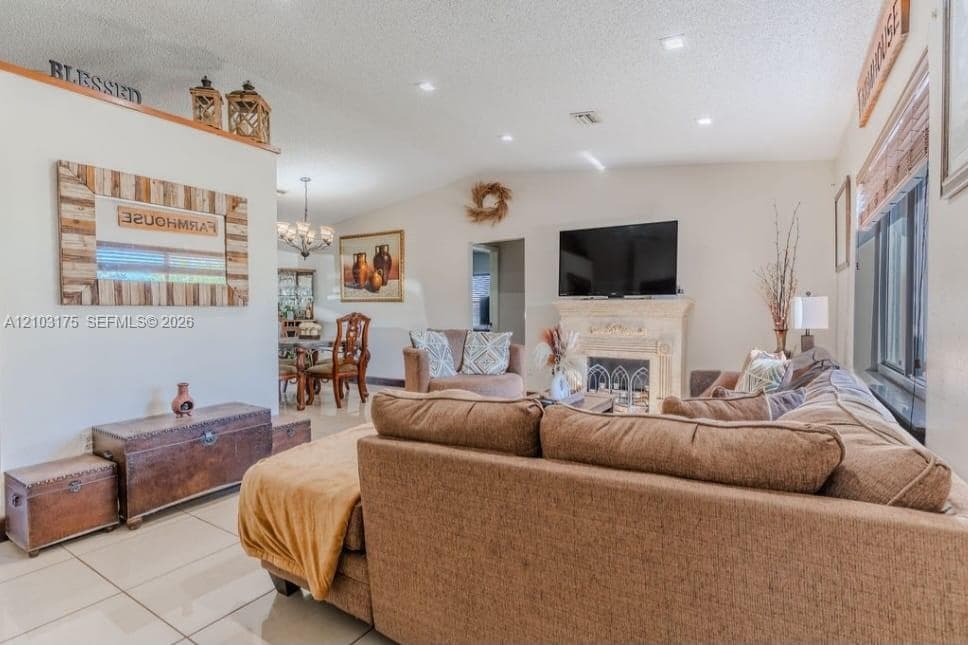 Open floor plan featuring recessed lighting, large-format tile flooring, and a stone-surround fireplace with detailed architectural molding