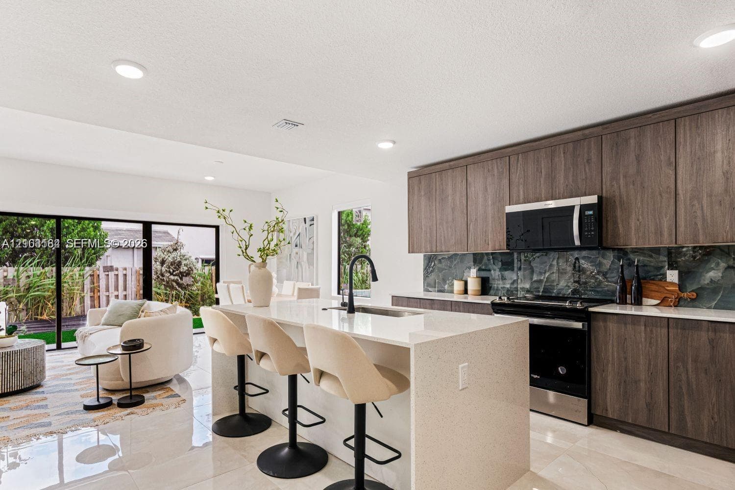 Kitchen featuring wood-finish cabinetry, stone-style backsplash, quartz countertops, central island, and recessed lighting