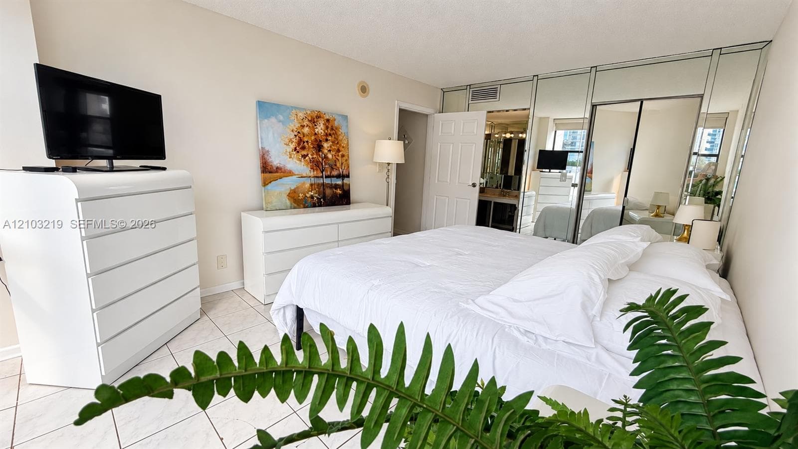 Room featuring floor-to-ceiling mirrored closet doors and neutral tile flooring