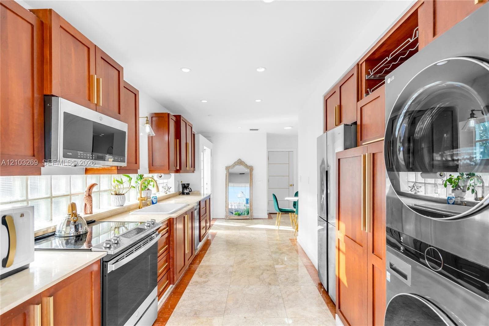 Kitchen featuring wood cabinetry, stone tile flooring, recessed lighting, glass block backsplash, and integrated stainless steel appliances