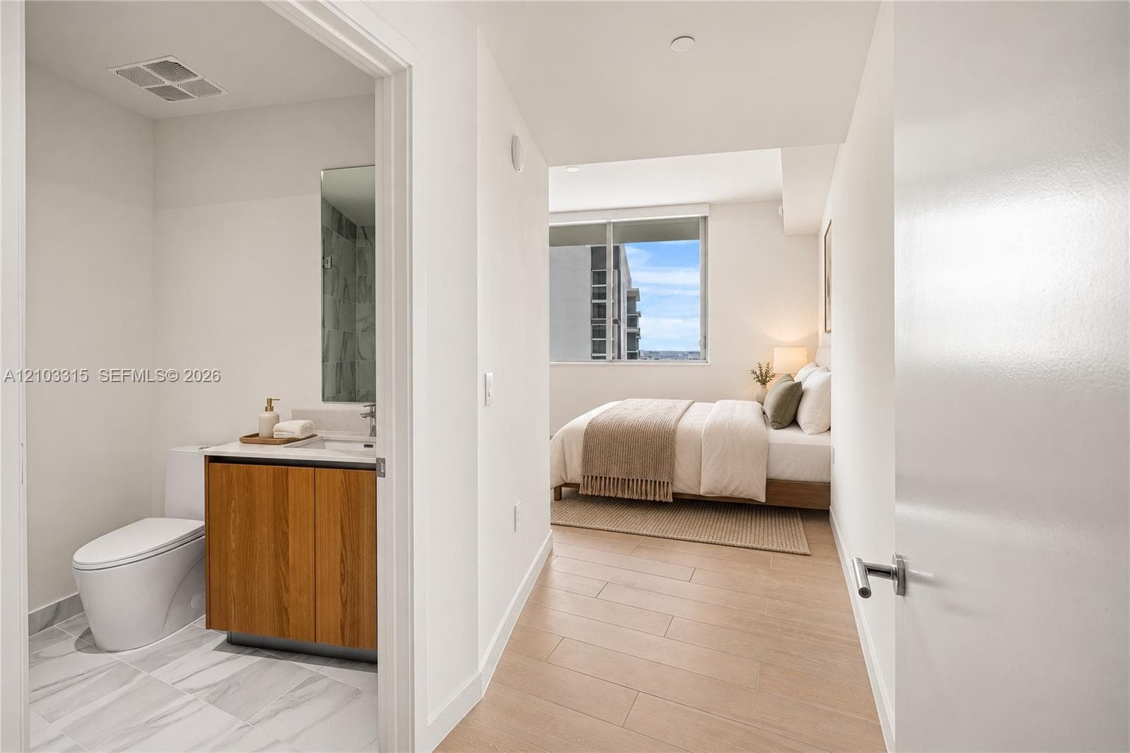 Modern bathroom with a wood-finish vanity, white countertop, and tiled flooring
